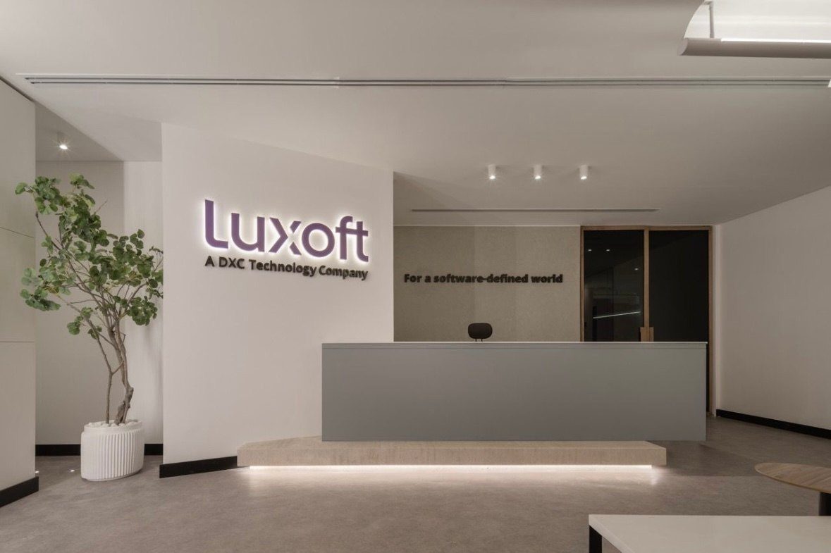 Reception with a white desk, Luxoft signage and pale timber flooring