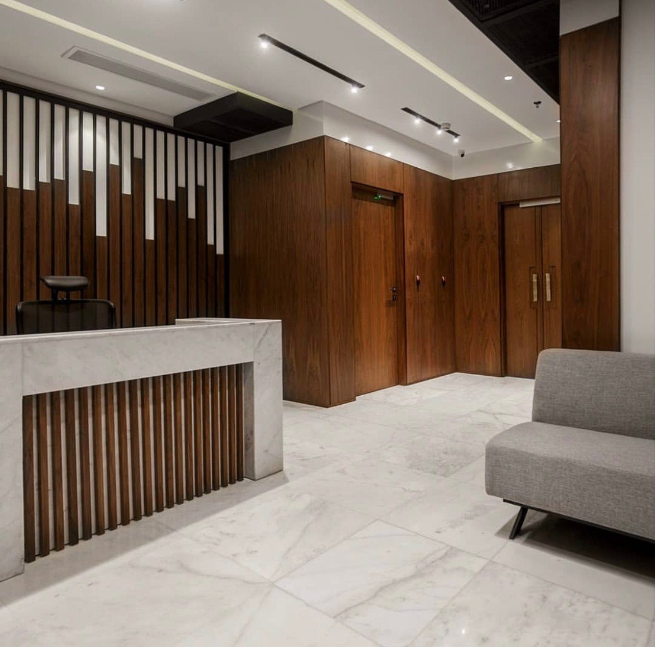 Reception with a slatted walnut screen and marble-topped desk